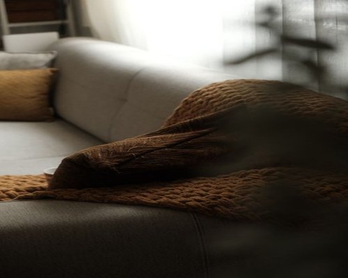 A peaceful view of a living room sofa with soft pillows during sunset, emphasizing deep rest after a hard transit day